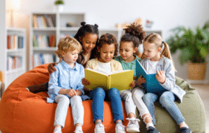 Group of diverse children sitting together on a bean bag, reading books and learning about financial literacy for kids in a classroom or library setting.